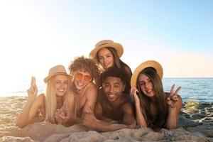 Group of friends having fun on the beach. Concept of summertime photo