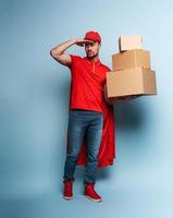 Courier acts like a powerful superhero. Concept of success and guarantee on shipment. Studio cyan background photo