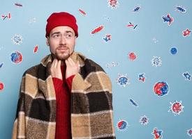 Boy caught a cold and is surrounded by viruses and bacteria. Studio on Cyan background photo