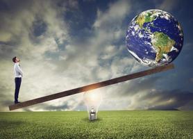 Businessman uses a lightbulb ad lever to lift the World. Earth provided by Nasa. photo