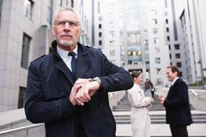 Businessman watches the clock waiting for a business appointment outdoors photo