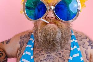 Fat angry man with beard and wig smokes cigarettes photo