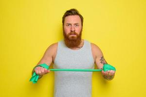 Man with beard and tattoos trains with a rubber band photo