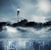 Businessman on a ladder escapes from crisis and looking for a new way photo