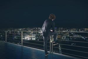 Businessman looks at the city during night. Future and new business opportunity concept photo