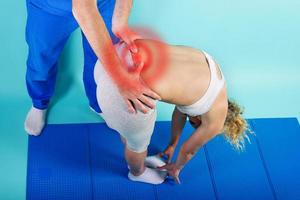 Girl performs exercises with a physiotherapist. Cyan background photo