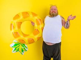 Fat thoughtful man with wig in head is ready to swim with a donut lifesaver photo