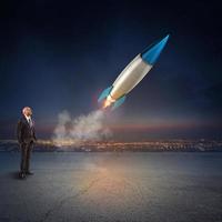 Businessman looks start a missile. Concept of company startup and new business. 3D Rendering. photo