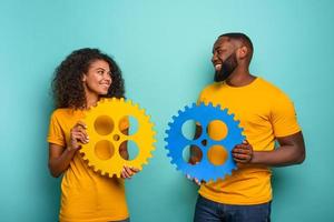 Couple with gears in hand over light blue background. Concept of integration, union and partnership photo