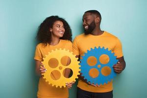 Couple with gears in hand over light blue background. Concept of integration, union and partnership photo