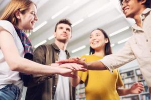 Universidad estudiantes poner su manos juntos. concepto de trabajo en equipo y camaradería foto