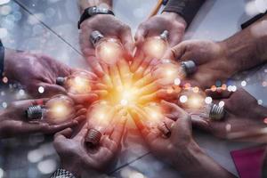 Teamwork and brainstorming concept with businessmen that share an idea with a lamp. Concept of startup photo