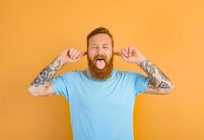 Man with beard and tattoo sticks his tongue out photo