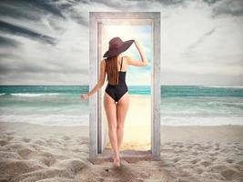 Woman crosses a door on the beach leading to the summer season. photo