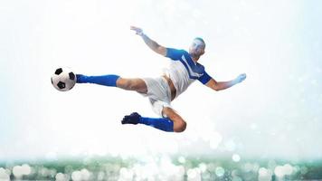 Soccer striker hits the ball with an acrobatic kick in the air on white background photo