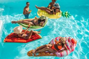 Group of friends in swimsuit enjoy in a swimming pool photo