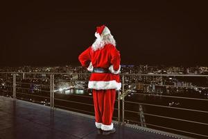 Christmas is coming. Santa Claus on a roof view city photo