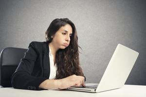 Bored woman snorts in the office while working on the laptop photo