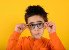 Child tries new glasses to see better. yellow background photo