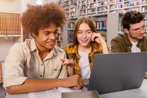 Universidad estudiantes son estudiando en un biblioteca juntos como trabajo en equipo para preparación foto