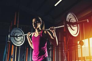 Athletic girl works out at the gym with a barbell photo