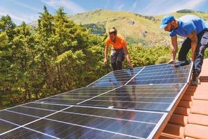 Workers assemble energy system with solar panel for electricity and hot water photo