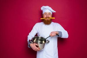 sorprendido cocinero con barba y rojo delantal es Listo a cocinar foto