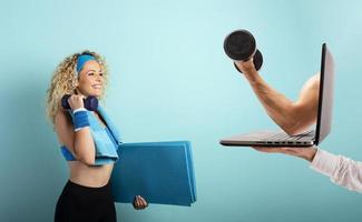 Girl with handlebars ready to start the gym online with a computer. cyan background photo