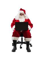 Santa claus works with his laptop for christmas photo