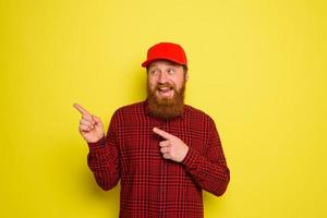 Happy delivery man with hat and beard indicates something photo