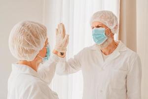 Doctors with mask and face protector give each other a 5 with their hand photo