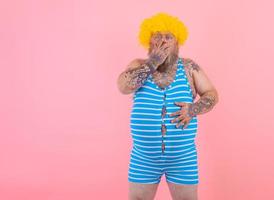 Amazed man with yellow wig and swimsuit has stomachache photo