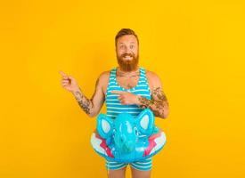 Happy man with inflatable donut with elephant is ready to swim photo