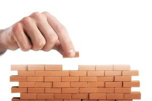 Businessman puts a brick to build a wall. Concept of new business, partnership, integration and startup photo