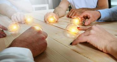 Teamwork and brainstorming concept with businessmen that share an idea with a lamp. Concept of startup photo