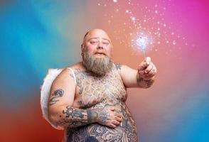 Fat happy man with beard ,tattoos and wings acts like an magic fairy photo