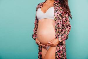 Pregnant woman expecting a child caresses her belly photo