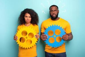 Couple with gears over light blue background. Concept of integration, union and partnership photo