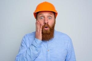 Isolated amazed architect with beard and orange helmet photo