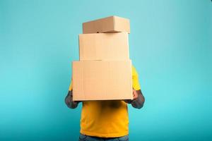 Man is hidden by too many received packages. Cyan background photo