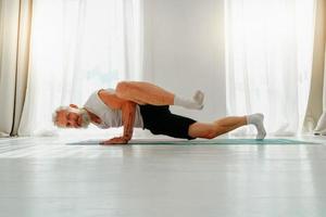 Sportive man does yoga exercise at home photo