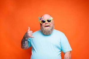 Fat happy man with beard, tattoos and sunglasses is ready for the summer photo