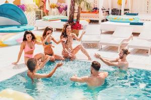 grupo de amigos en traje de baño disfrutar en un nadando piscina foto