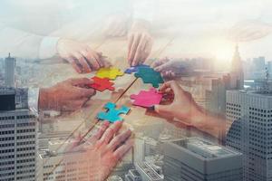 Business team connect pieces of puzzle like a teamwork and partners on city buildings background photo