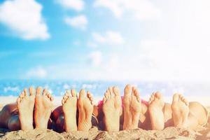 Group of friends having fun on the beach with their foots. Concept of summertime photo