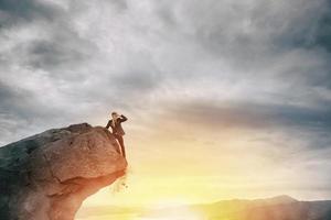 Businessman on the peak of a mountain to find new business photo