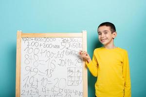 Child solves mathematical problem with abacus. Cyan background photo