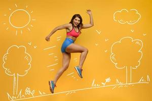 Sport woman runs on yellow background. Happy and joyful expression. photo