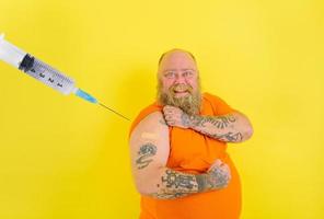 Happy man with beard and tattoos does the vaccine against covid-19 photo