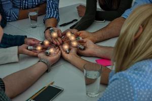 Teamwork and brainstorming concept with businessmen that share an idea with a lamp. Concept of startup photo